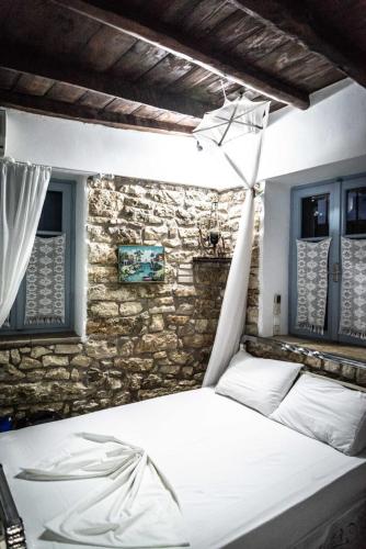 a bedroom with a white bed with a stone wall at Petrinο Katochori in Katokhórion