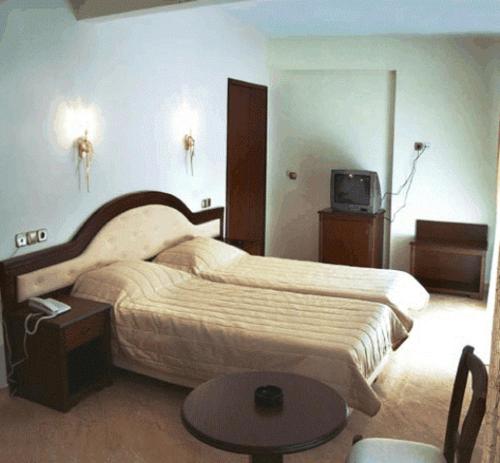 a bedroom with two beds and a table and a tv at Filippos in Nea Moudania