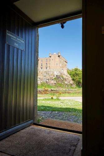 a door to a building with a castle in the background at Dunvegan Castle Laundry Cottage in Dunvegan
