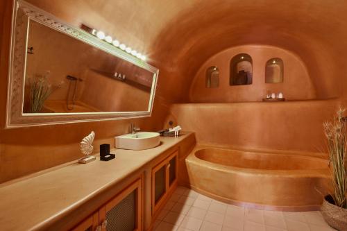 a bathroom with a tub and a sink and a mirror at Luna Santorini Suites in Pirgos