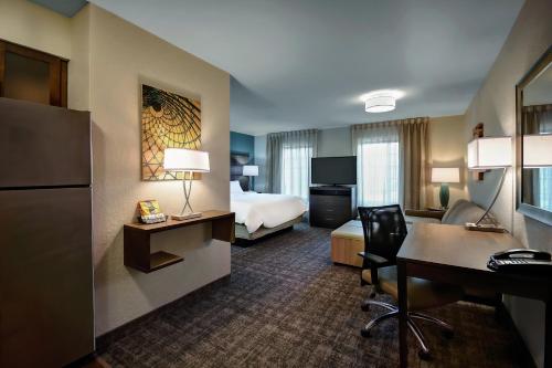 a hotel room with a bed and a desk at Staybridge Suites - Holland by IHG in Holland