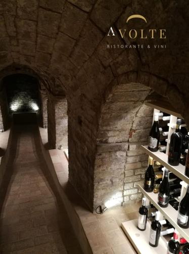 a wine store in a stone building with bottles on shelves at Villa Anitori Prestige Relais & Spa in Loro Piceno