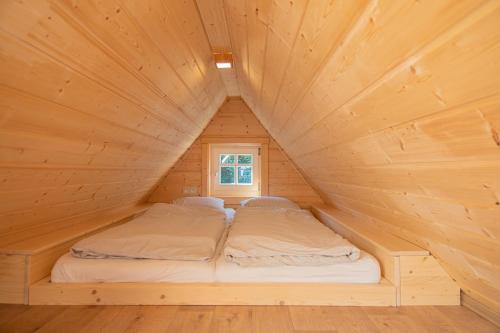two beds in a wooden cabin with a window at Chatička u řeky - Kouty nad Desnou in Loučná nad Desnou
