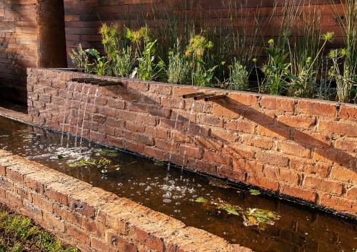 a brick retaining wall with a water fountain at The Doors Inn in Mokopane