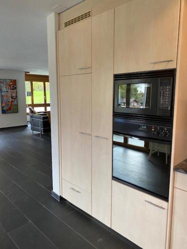 a kitchen with a microwave and a living room at Luxury family apartment Engelberg in Engelberg