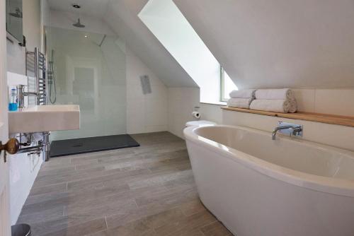 baño con bañera blanca grande y lavamanos en Dunvegan Castle The Farmhouse Cottage, en Dunvegan