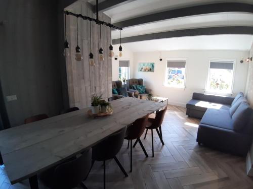 uma sala de estar com uma grande mesa de madeira e cadeiras em Luxe chalet 'Wysha' em Sint-Annaland