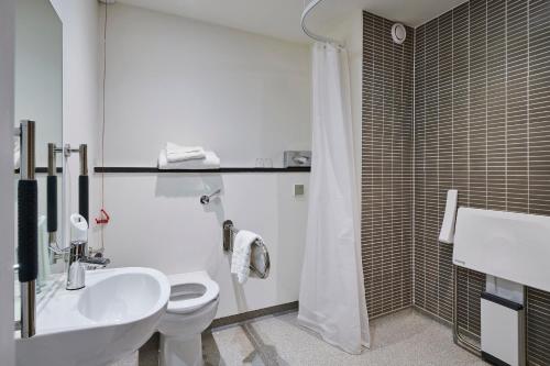a white toilet sitting next to a bath tub in a bathroom at Holiday Inn Leeds Garforth, an IHG Hotel in Garforth