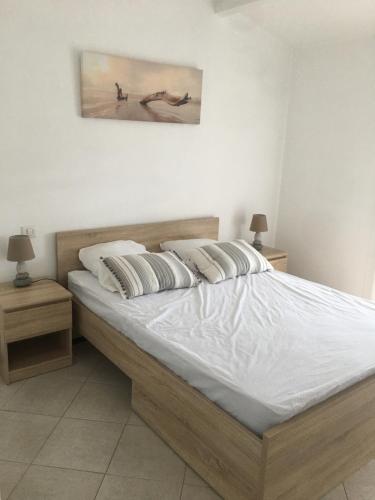 um quarto com uma cama grande com lençóis brancos e almofadas em maison en Camargue em Saintes-Maries-de-la-Mer