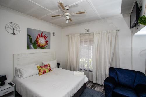 a bedroom with a bed and a chair and a window at WILLOW GUEST HOUSE in Boksburg