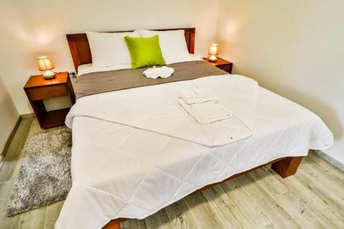 a bedroom with a large white bed with green accents at Simo apartments airport Podgorica in Podgorica