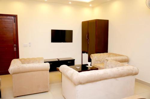 a living room with two chairs and a tv at Hotel Noor Plaza in Lahore