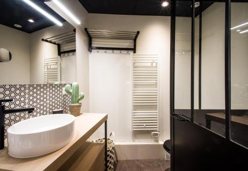 La salle de bains est pourvue d'un grand lavabo blanc et d'une douche. dans l'établissement So Sweet Capitole, à Toulouse
