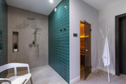 a bathroom with a shower with green tile on the wall at Śnieżka Exclusive Apartamenty in Kowary