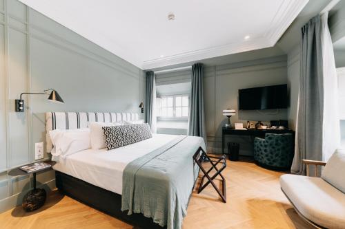 a bedroom with a large bed and a chair at Soho Boutique Colón in Málaga