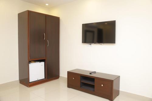 a living room with a tv and a cabinet at Hotel Noor Plaza in Lahore