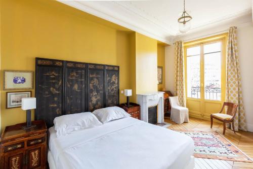 - une chambre avec un grand lit blanc et des murs jaunes dans l'établissement Veeve - Elegant Interiors in Bastille, à Paris