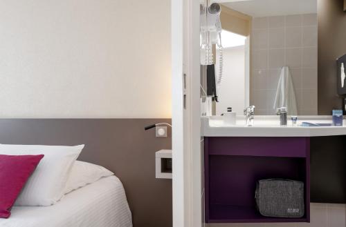 um quarto de hotel com uma cama e um lavatório em Kyriad Hotel Lyon Givors em Givors