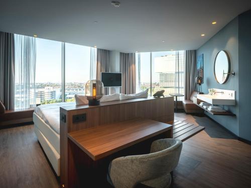 a hotel room with a bed and a desk and a large window at Van der Valk Hotel Amsterdam Zuidas -Rai in Amsterdam