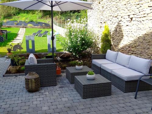 a patio with a couch and chairs and an umbrella at Les Myosotis Chambres d'hôtes - Sarreguemines in Zetting