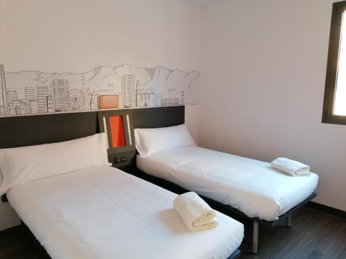 a hotel room with two beds and two lamps at easyHotel Malaga City Centre in Málaga