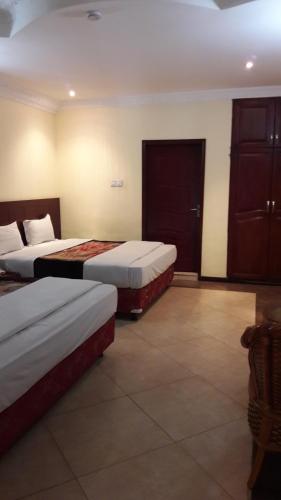 a hotel room with two beds in a room at Biraj International Hotel in Kampala