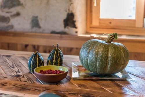 a table with three pumpkins and a bowl of cranberries at Baita dai Cotai in Groppe de Fora