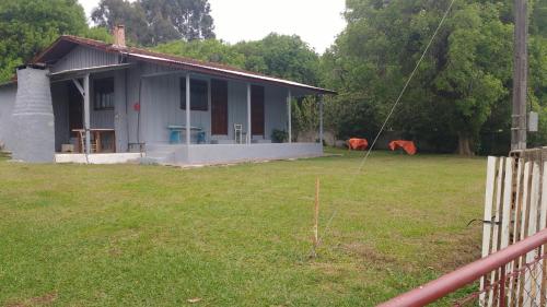ein kleines Haus in einem Hof mit einem Zaun in der Unterkunft Casa chácara in Cará-Cará