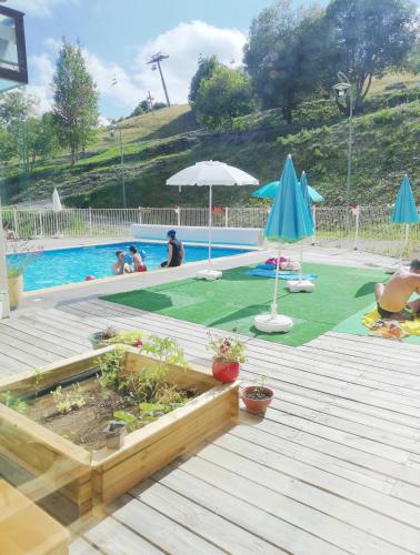 une terrasse avec une piscine, un parasol et des plantes dans l'établissement Résidence Goélia Les Terrasses du Corbier, au Corbier
