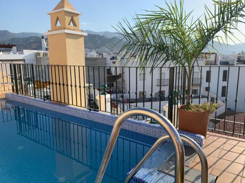 a balcony with a swimming pool and a clock tower at Apartamentos Nerjaluna in Nerja