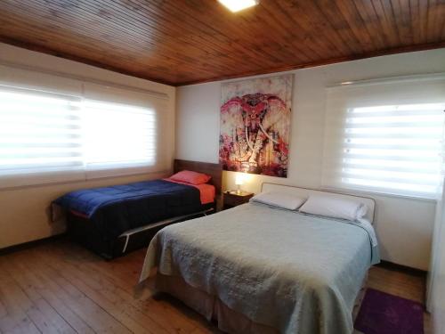 a bedroom with two beds and two windows at Habitaciones Mar Azul in El Quisco