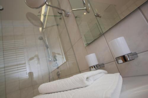 a bathroom with two white towels and a mirror at Seminarhotel Aurich in Aurich