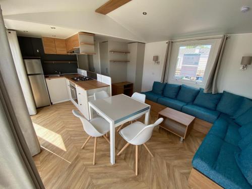 a living room with a blue couch and a table and chairs at Les dunes de contis in Saint-Julien-en-Born