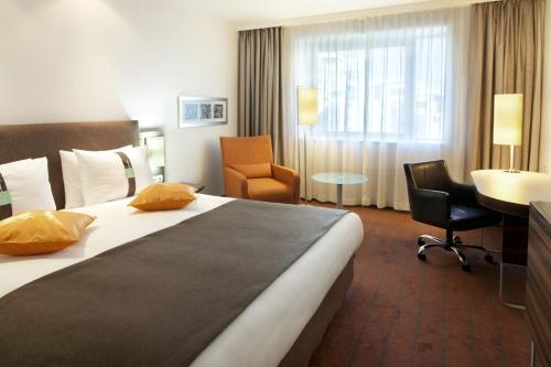 ein Hotelzimmer mit einem großen Bett und einem Schreibtisch in der Unterkunft Holiday Inn Almaty, an IHG Hotel in Almaty