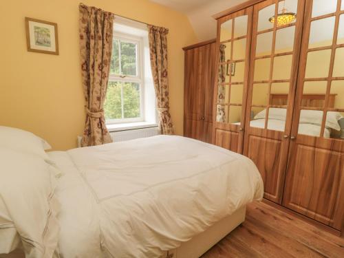 1 dormitorio con 1 cama y un gran armario de madera en Red Squirrel Cottage, 5 Biddlestone, en Morpeth