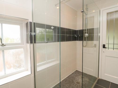a bathroom with a shower with a glass door at Red Squirrel Cottage, 5 Biddlestone in Morpeth