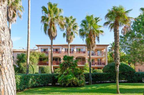 un bâtiment avec des palmiers devant dans l'établissement Résidence Pierre & Vacances La Pinède, à Hyères