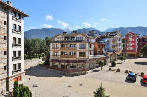 a group of buildings with mountains in the background at Pirin Golf & Country Club Apartment Complex in Bansko