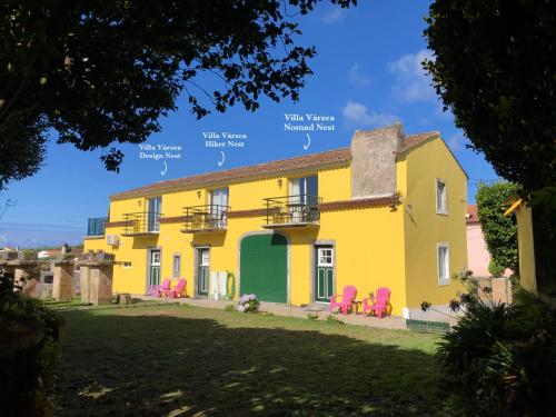 a yellow house with pink chairs in a yard at Villa Várzea Design Nest in Várzea