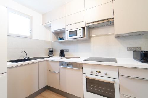 une cuisine blanche avec un évier et un micro-ondes dans l'établissement Cottage 