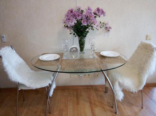 プーシキンにあるклассная квартираのガラステーブル(椅子2脚付)と紫の花瓶
