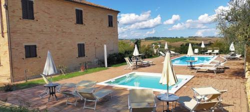 a pool with chairs and umbrellas next to a building at Il Giardino Degli Ulivi in Appignano