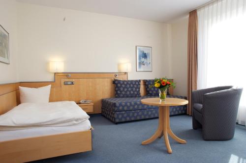 ein Hotelzimmer mit einem Bett, einem Sofa und einem Tisch in der Unterkunft Seminarhotel Aurich in Aurich