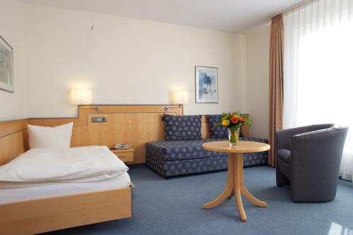 a hotel room with a bed and a couch and a table at Seminarhotel Aurich in Aurich