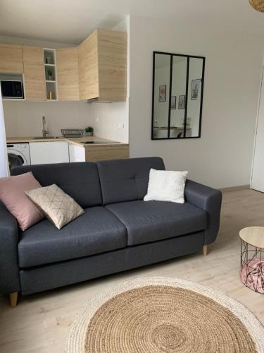 a living room with a blue couch and a kitchen at Chaleureux Studio 30m2 - Au pied de la Gare - PARKING in Cergy