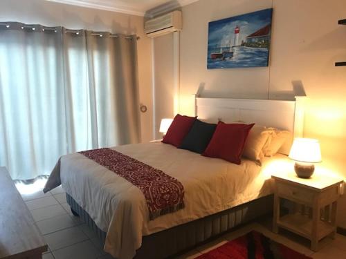 een slaapkamer met een groot bed met rode kussens bij 111 Lescalier Cabanas - Amanzimtoti in Amanzimtoti