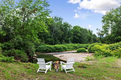 two white chairs sitting on the grass near a pond at Town & Country Stowe in Stowe