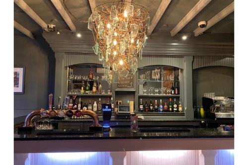 a bar with a chandelier and a bar with alcohol at OYO The Leven in Stokesley