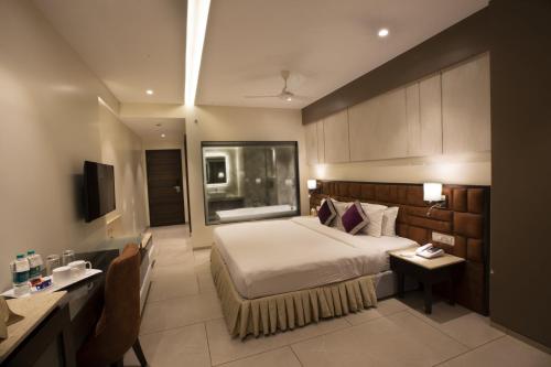 a hotel room with a bed and a desk and a room at The Flora Grand, Vasco, Goa in Vasco Da Gama
