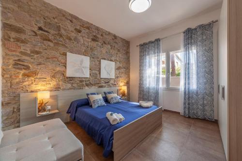 sypialnia z niebieskim łóżkiem i kamienną ścianą w obiekcie Prima dell'Elba Family Apartments w mieście Piombino